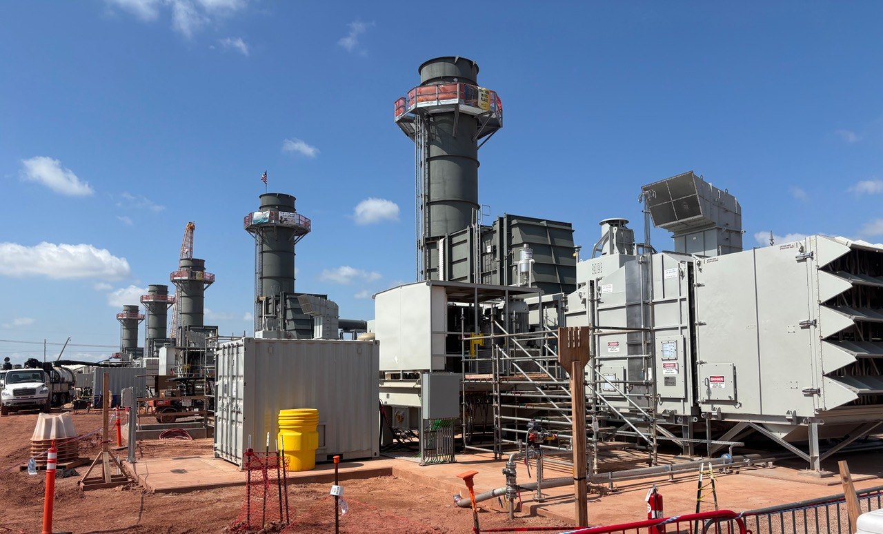 Ground-level gas turbines at Crusoe’s Abilene campus, showing turbine enclosures, ductwork, stairs and tall exhaust stacks.